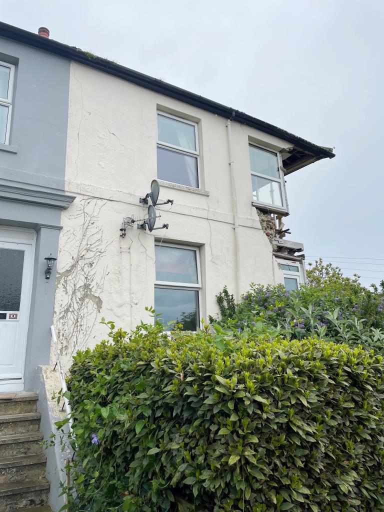Lot: 150 - END-TERRACE PROPERTY FOR RECONSTRUCTION ARRANGED AS TWO FLATS - Picture of front of house with large area missing following a fall due to subsidence